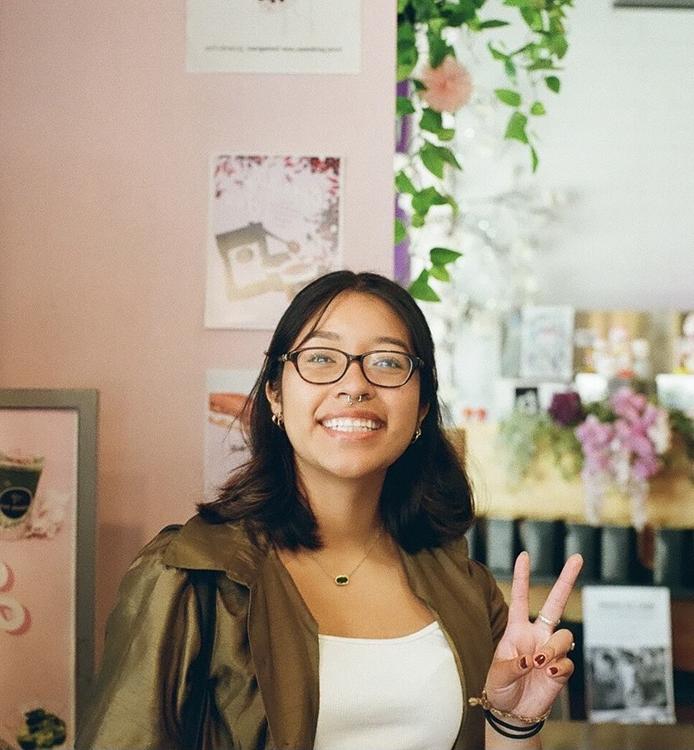 Woman in glasses making a peace sign with her fingers